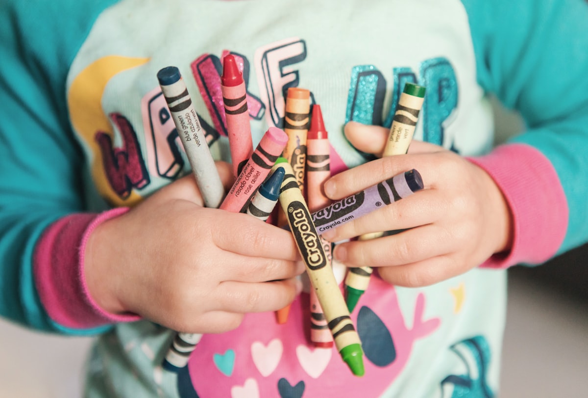 A child's hand holding a fistful of colorful crayons